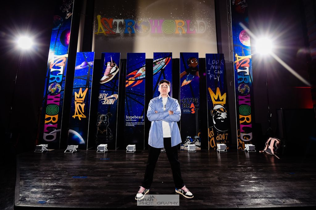 A man is standing on a stage in front of a wall that says astroworld