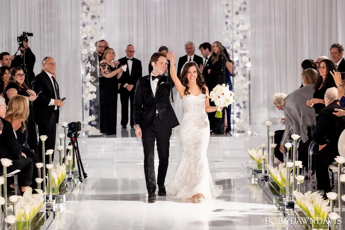 A bride and groom are walking down the aisle at their wedding.