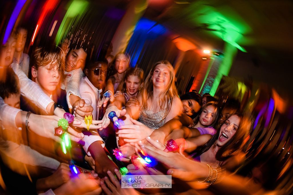A group of people are holding each other 's hands at a party.