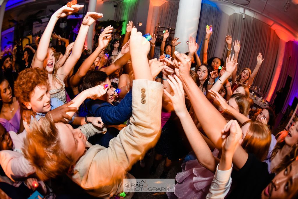 A group of people are dancing in a room with their hands in the air.