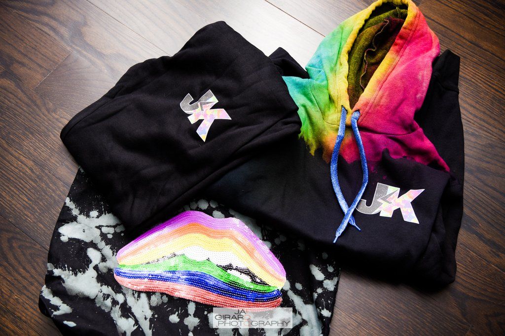 A black hoodie with a rainbow hood sits on a wooden table