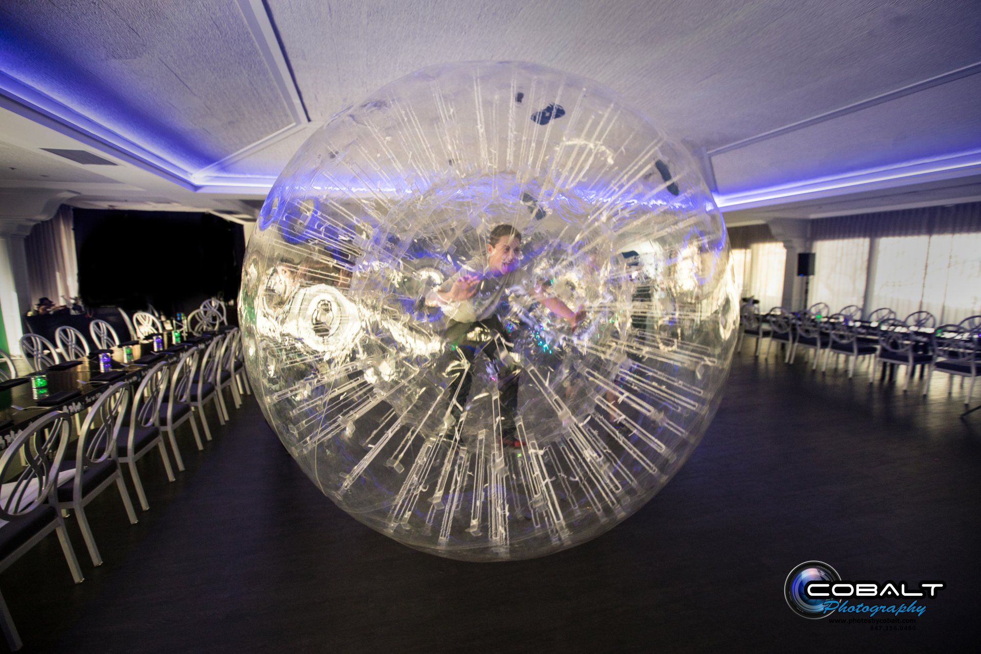 A person is riding a hamster ball in a room.