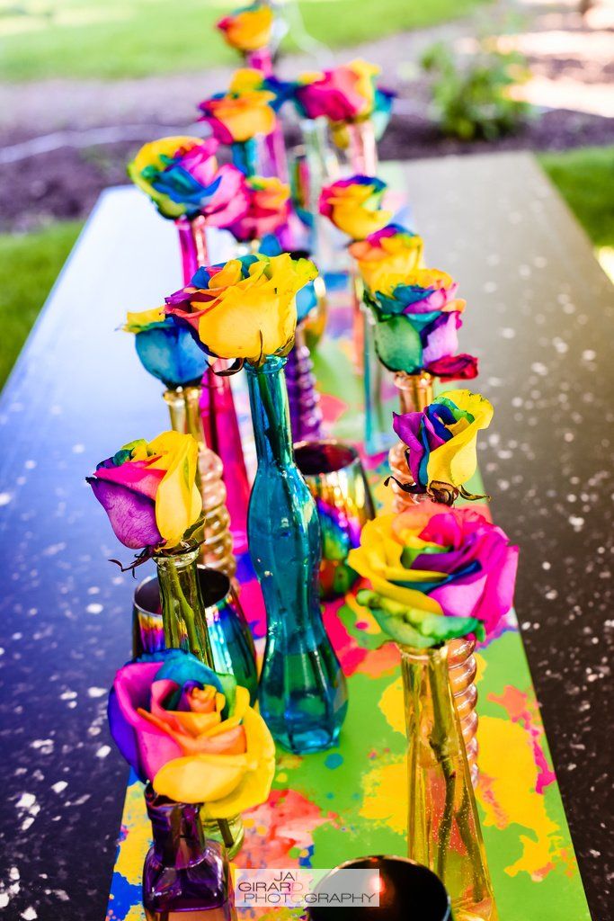 Rainbow colored roses in vases on a table
