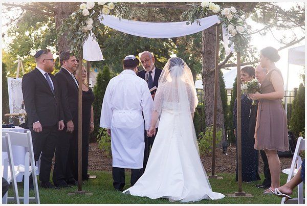 A bride and groom are holding hands during their wedding ceremony