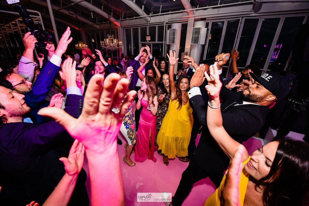 A group of people are dancing at a party with their hands in the air.