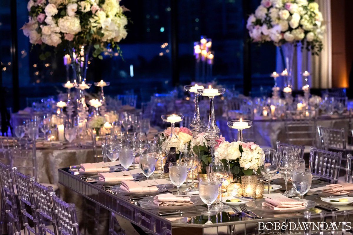 A table set for a wedding reception with flowers and candles on it.