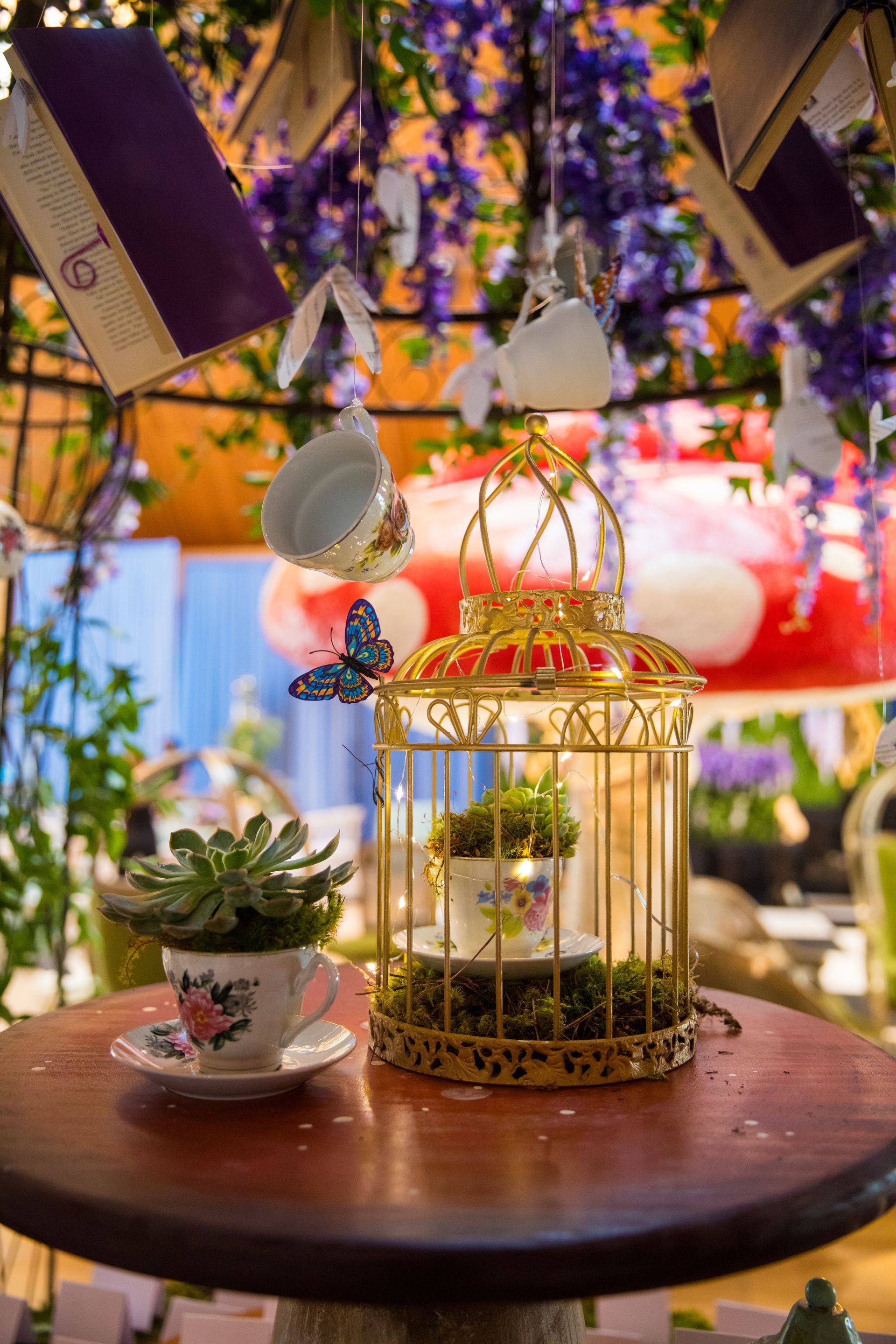 A table with a bird cage , cups and saucers on it.