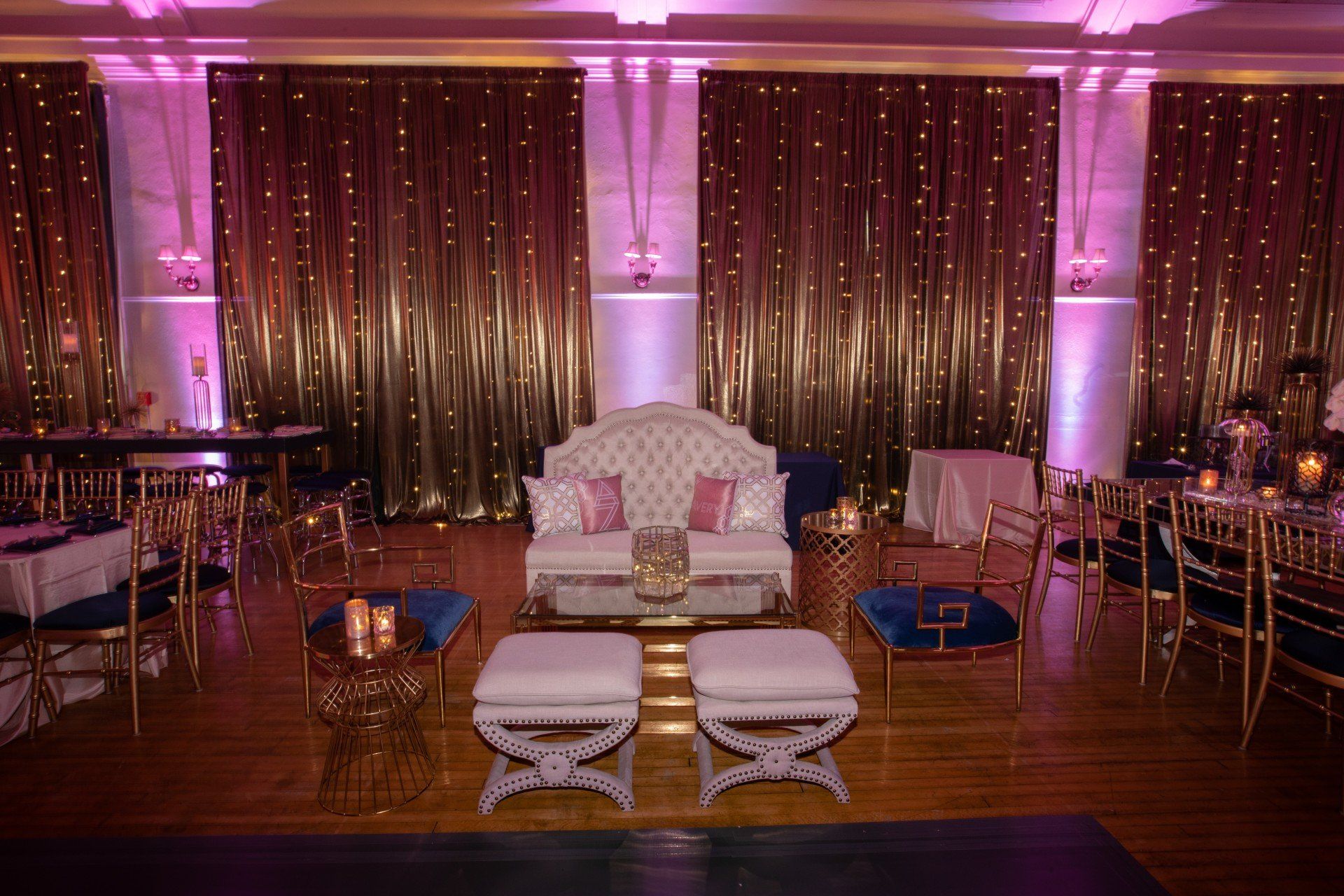 There is a couch in the middle of the room with tables and chairs.