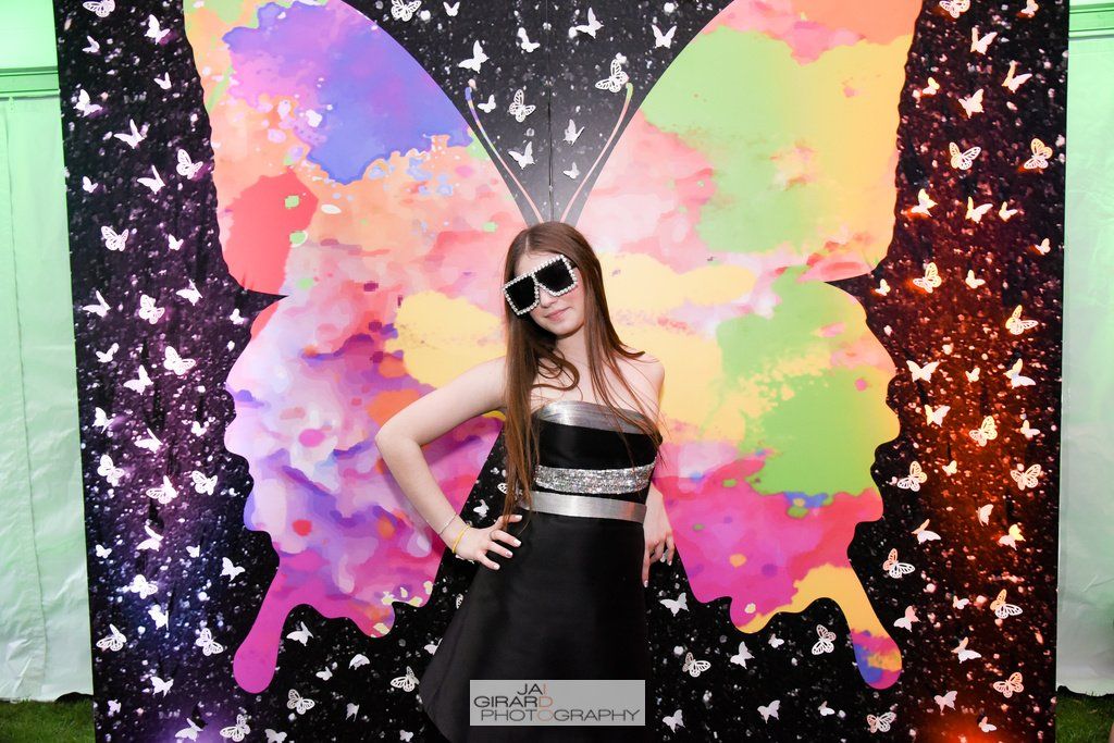 A woman in a black dress is standing in front of a butterfly backdrop.