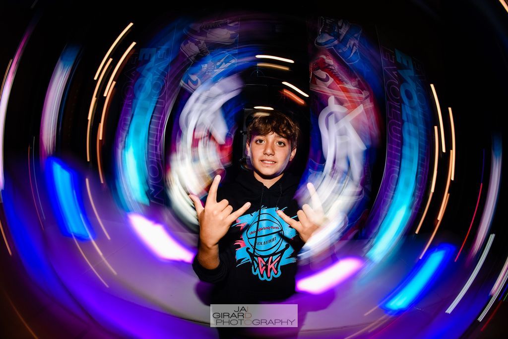 A young boy is standing in a circle of lights making a peace sign.
