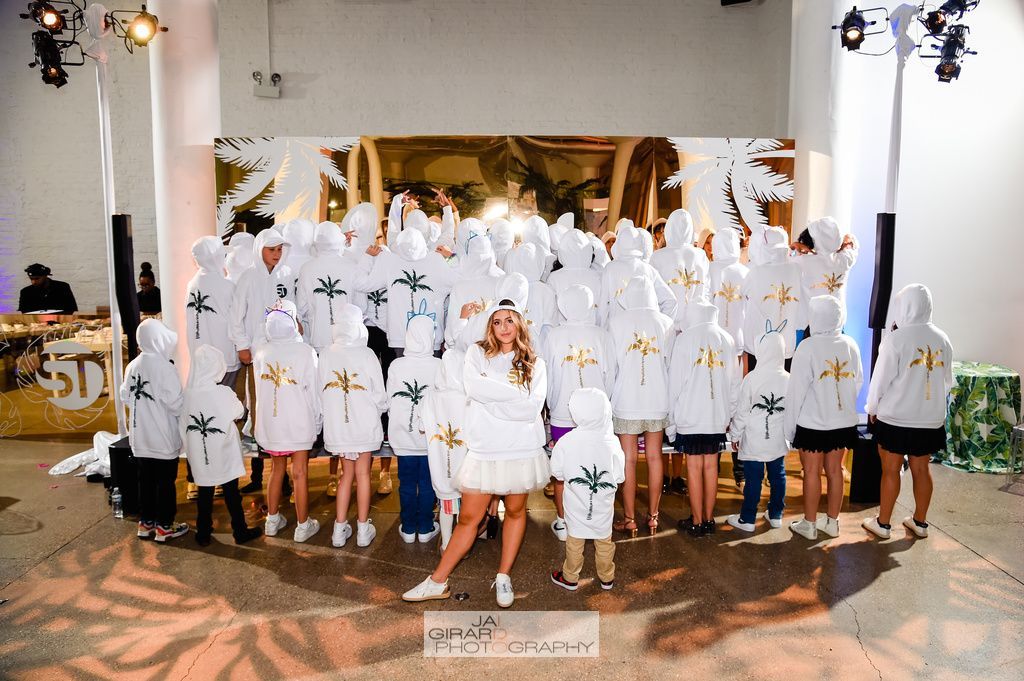A group of people wearing white hoodies are posing for a picture.