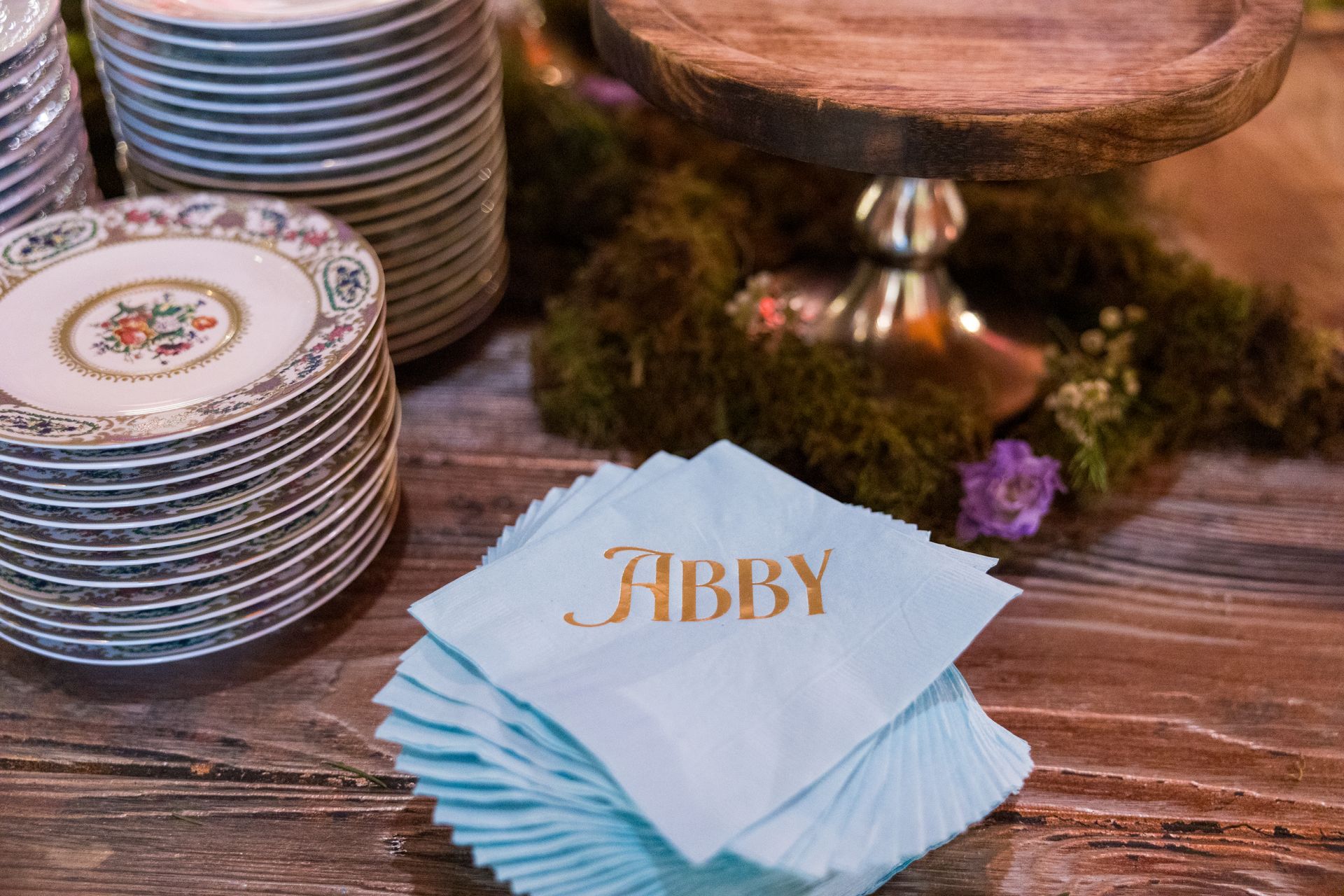 A stack of napkins with the name abby written on them on a wooden table.