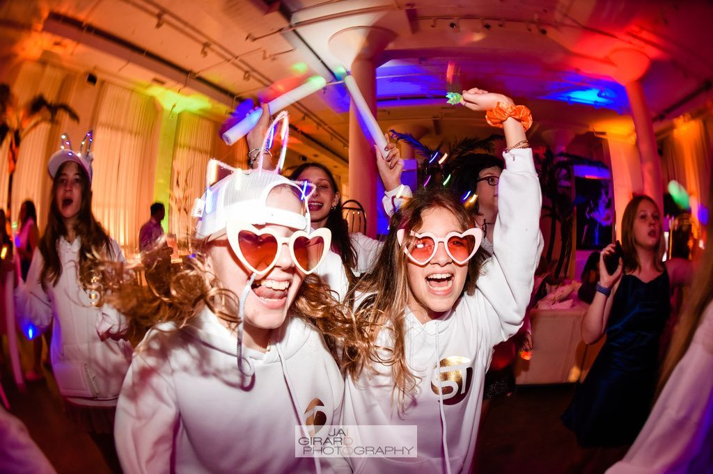 A group of young girls are dancing at a party wearing glow in the dark glasses.