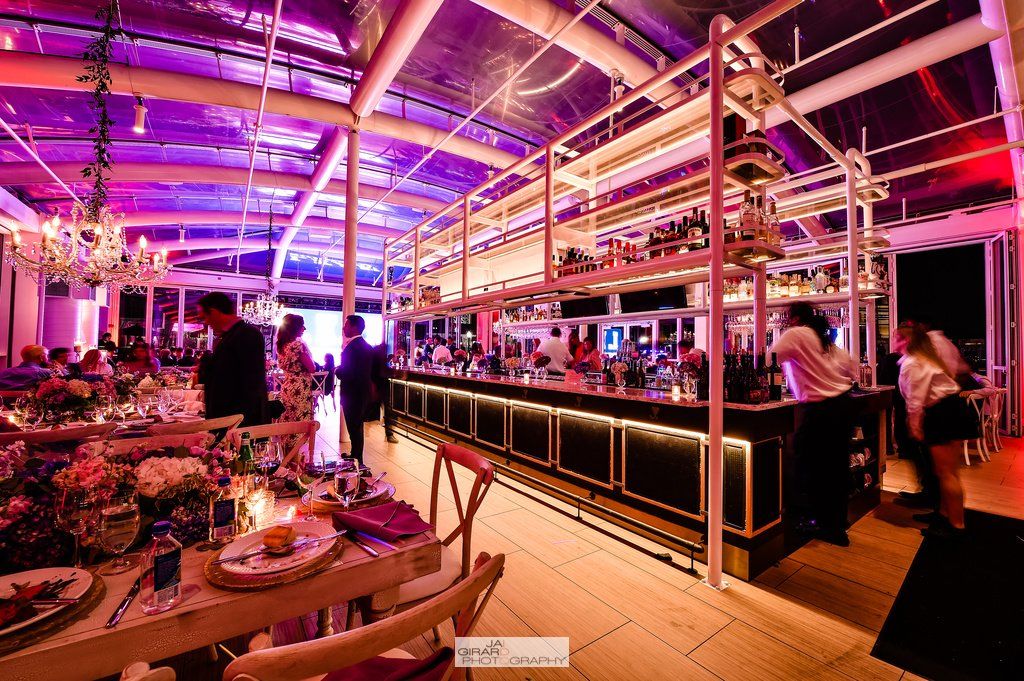 A large room with tables and chairs and a bar.