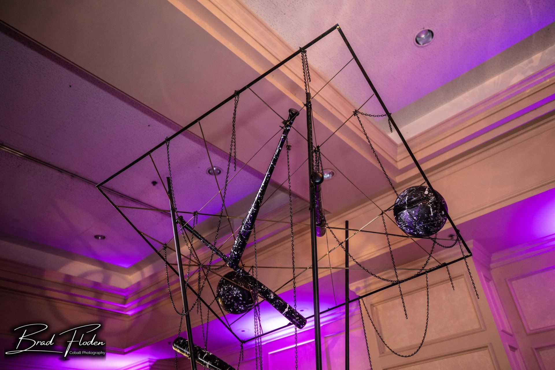 A large sculpture is hanging from the ceiling in a room with purple lights.