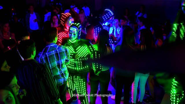 A group of people are dancing in a dark room with neon lights