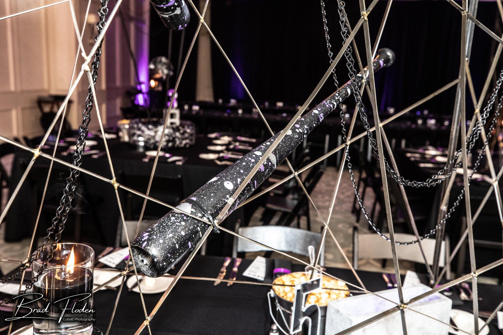 A baseball bat is hanging from a chain on a table.