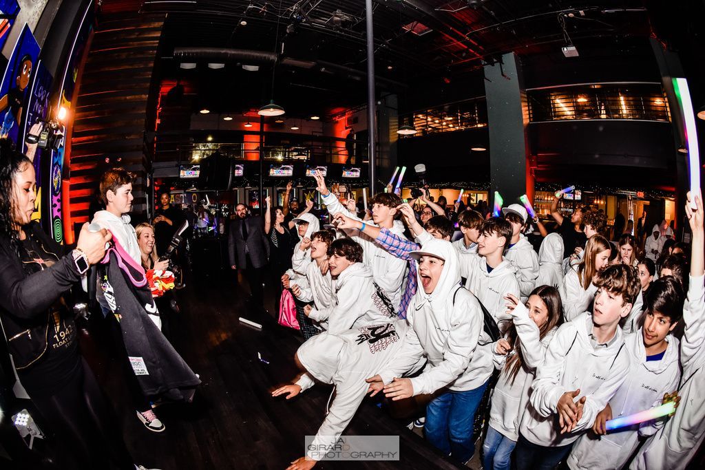 A large group of people are dancing in a dark room.