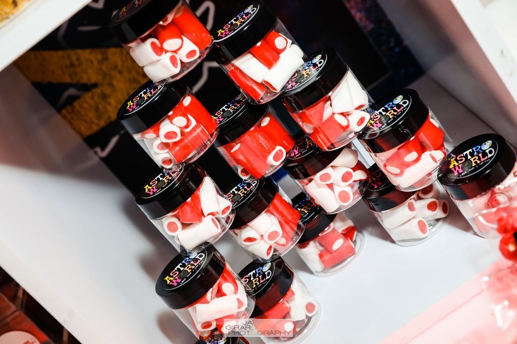A row of jars filled with red and white candy on a shelf.