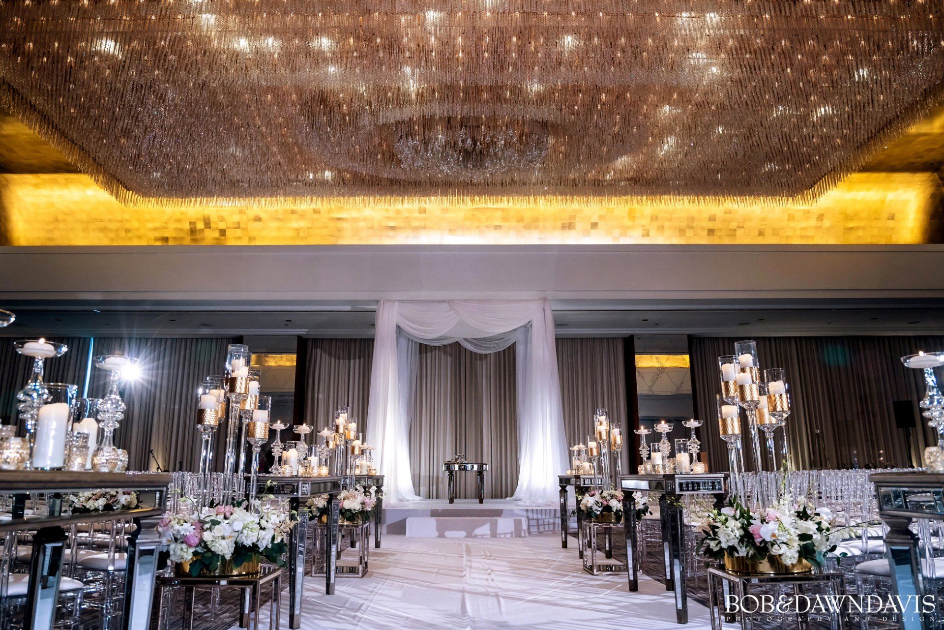 A wedding ceremony is taking place in a large room with a chandelier.