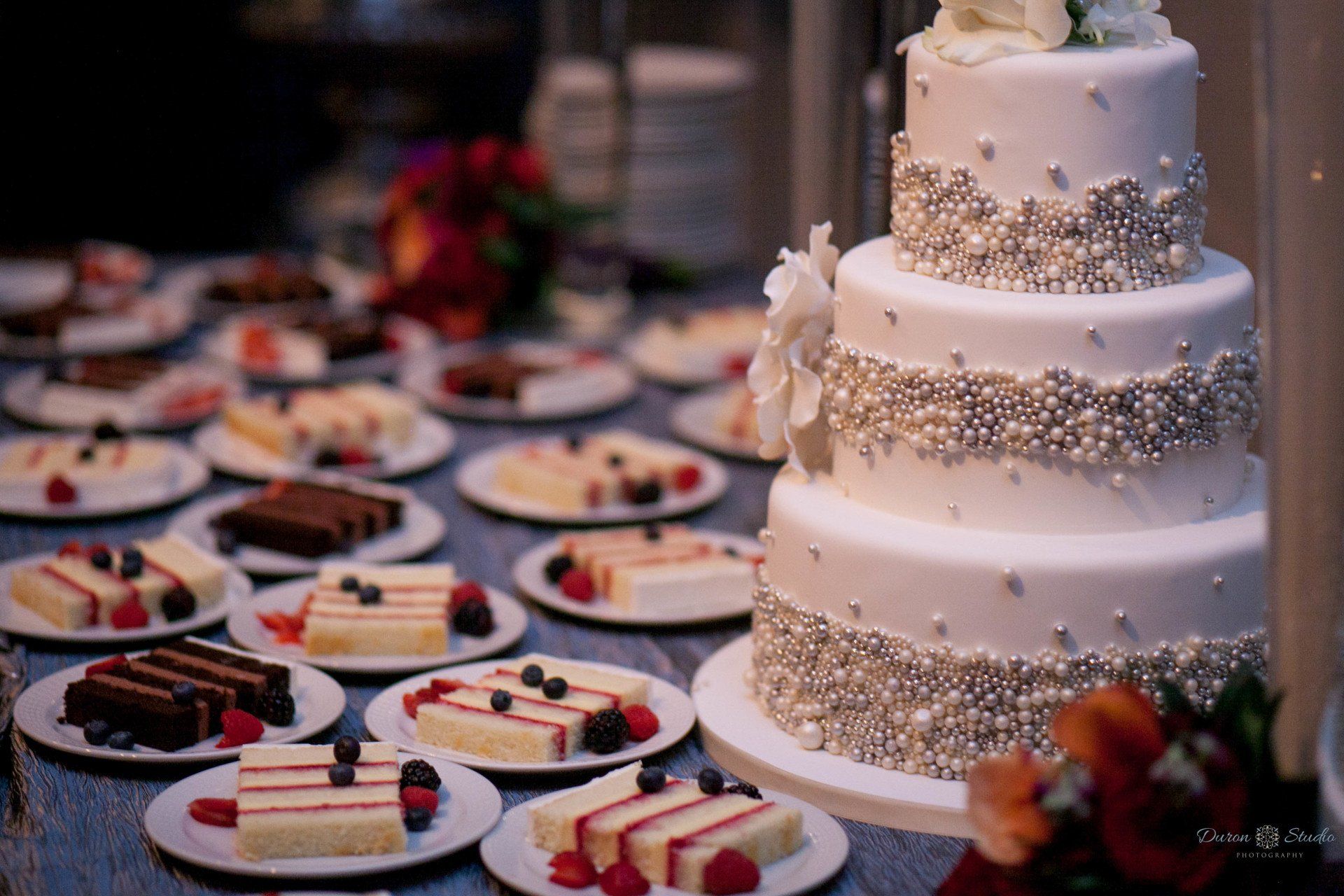A wedding cake is sitting on top of a table surrounded by desserts.