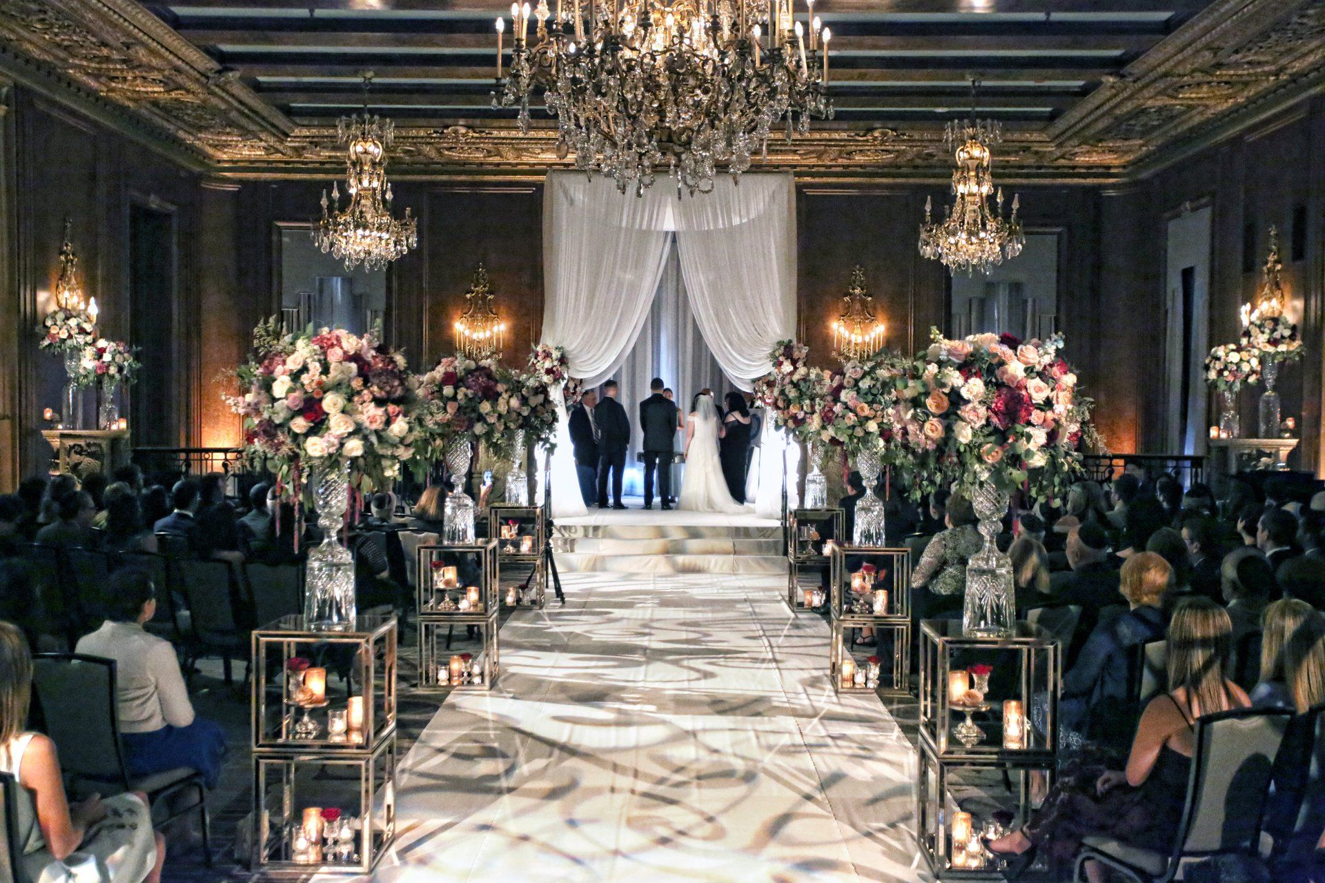A large room with a bride and groom standing in front of a crowd at a wedding ceremony.