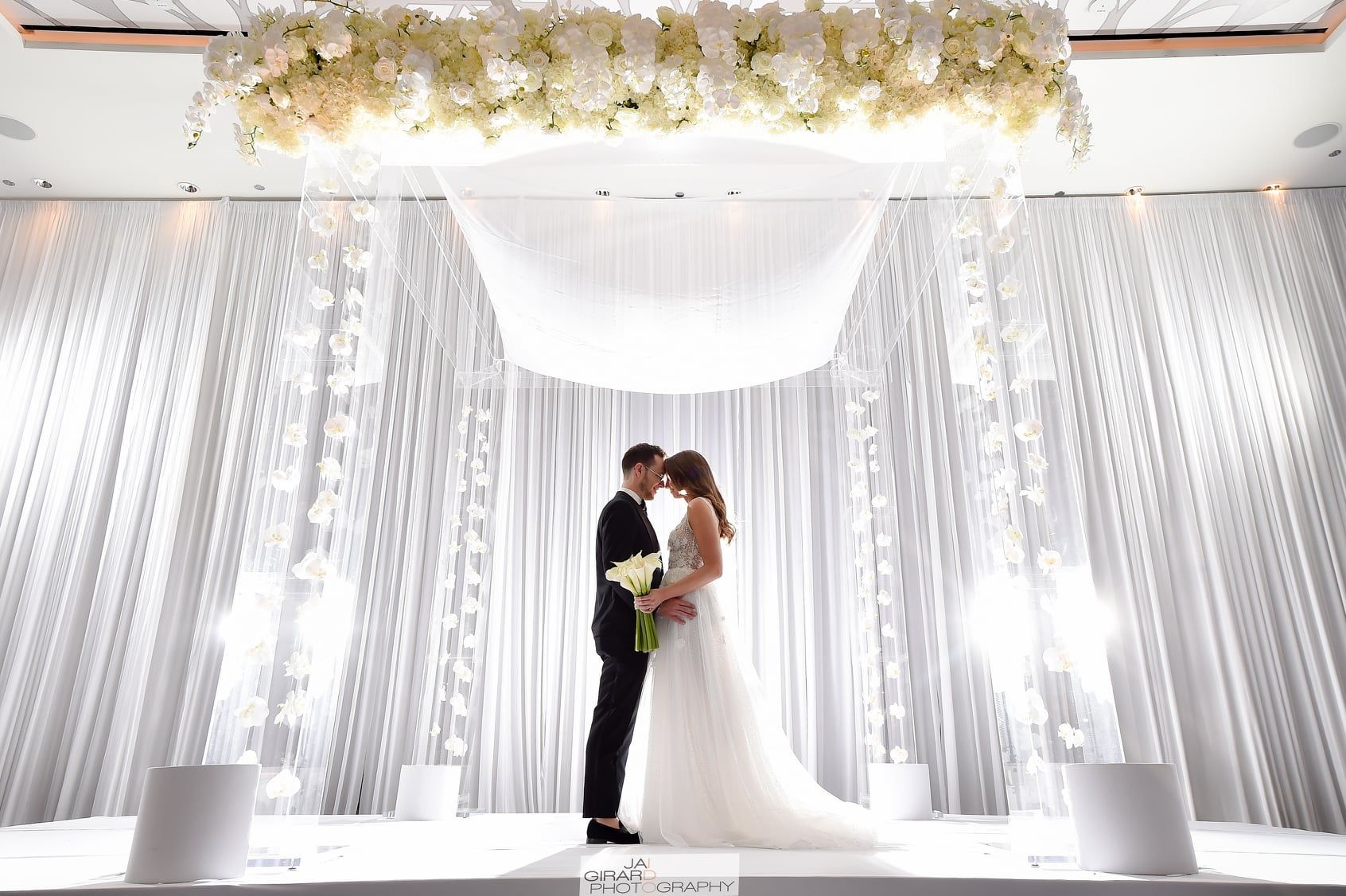 A bride and groom are kissing on a stage at their wedding.