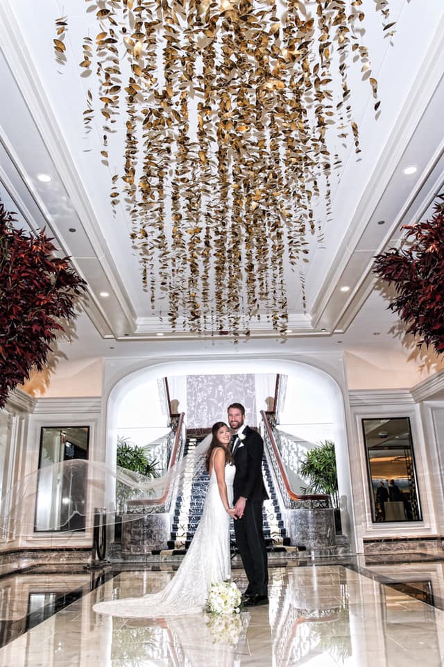 A bride and groom are posing for a picture in the lobby of a hotel.
