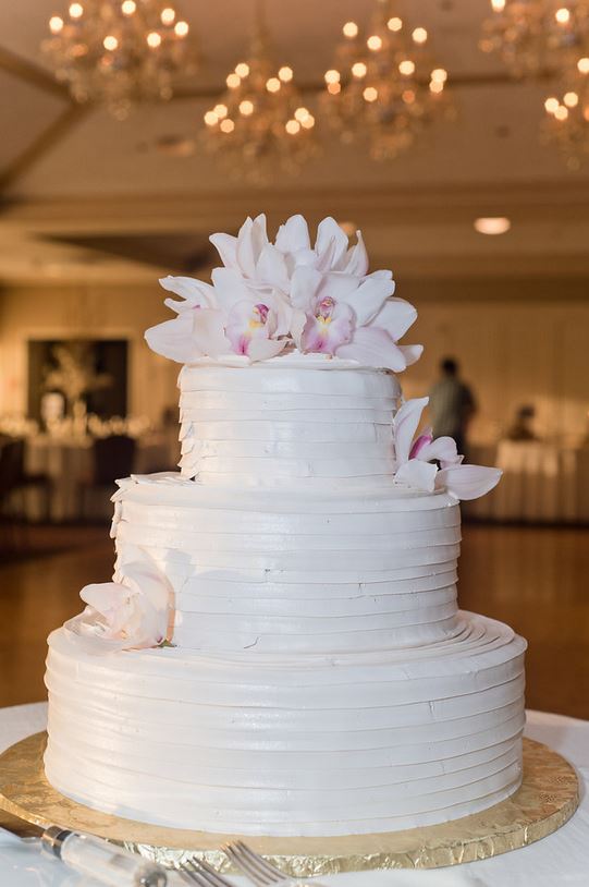 A white wedding cake with flowers on top is sitting on a table.