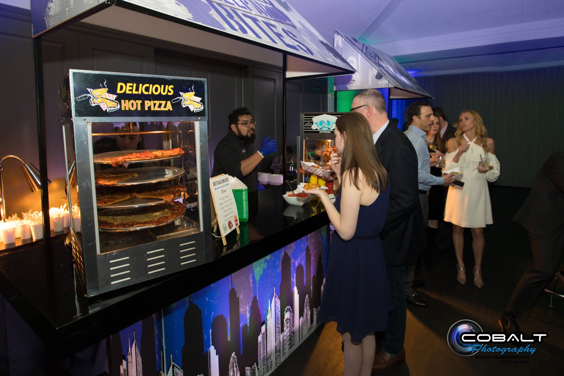 A group of people are standing around a hot pizza stand.