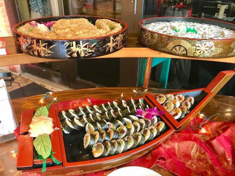 A boat shaped tray filled with sushi and rice on a table.