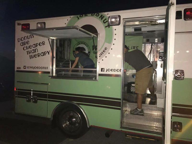 A man standing in front of a donut truck that says donuts are cheaper than therapy
