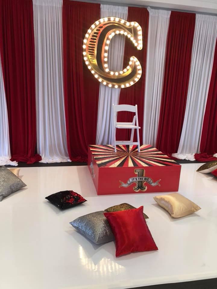 A chair is sitting on a table in front of a red and white curtain.