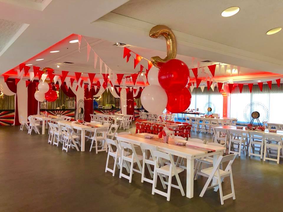 A room filled with tables and chairs decorated with red and white balloons.