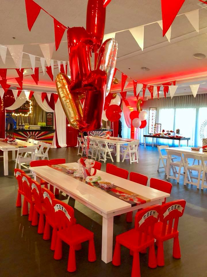 A room with tables and chairs and balloons hanging from the ceiling
