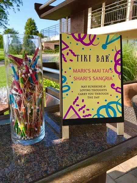 A sign that says tiki bar next to a glass of straws