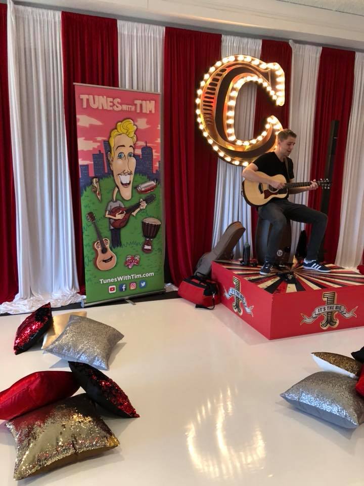 A man is sitting on a stage playing a guitar.