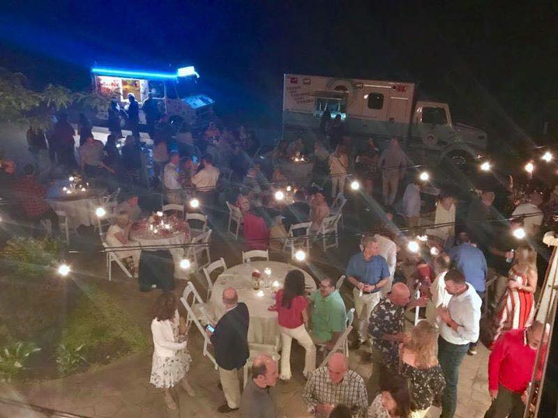 A large group of people are sitting at tables outside at night.