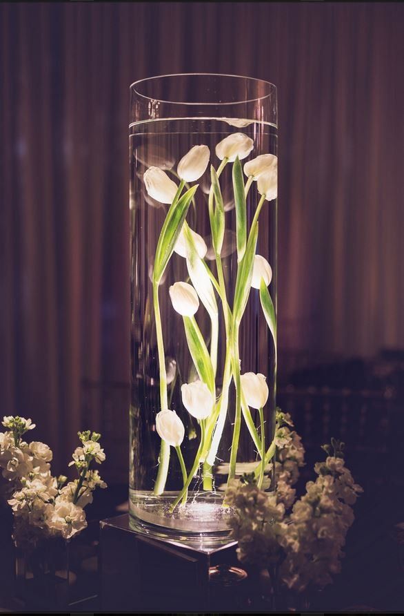 A vase filled with water and white flowers on a table.