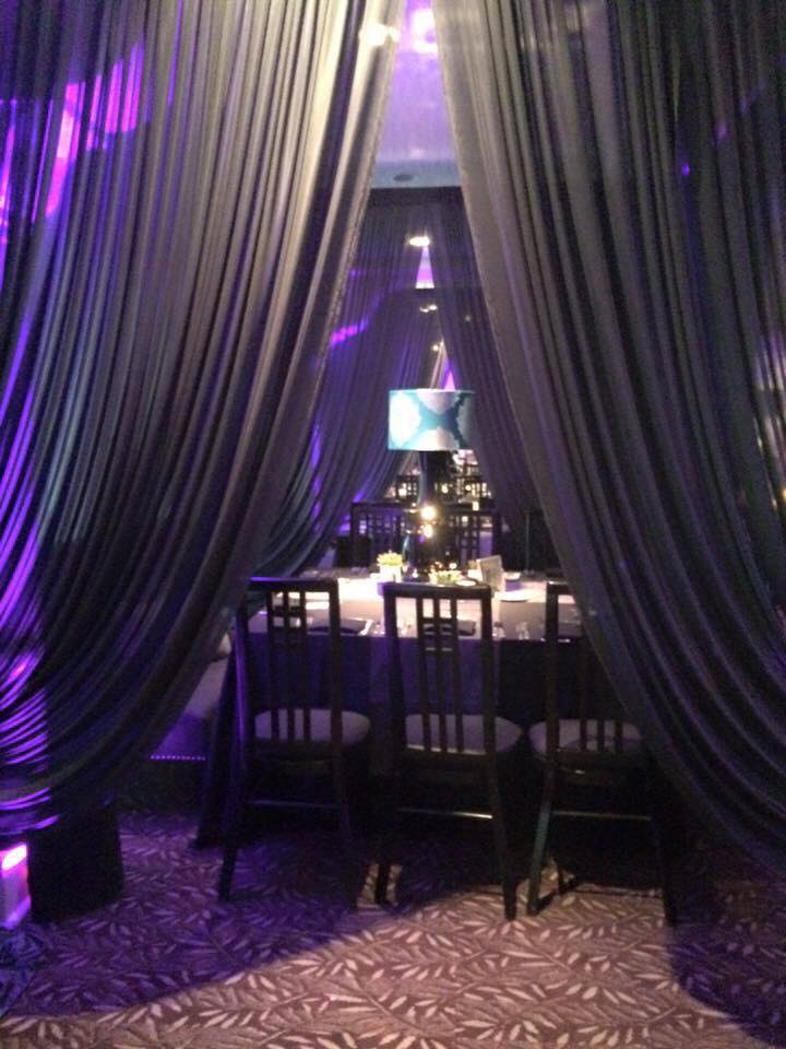 A dining room with a table and chairs and purple curtains.