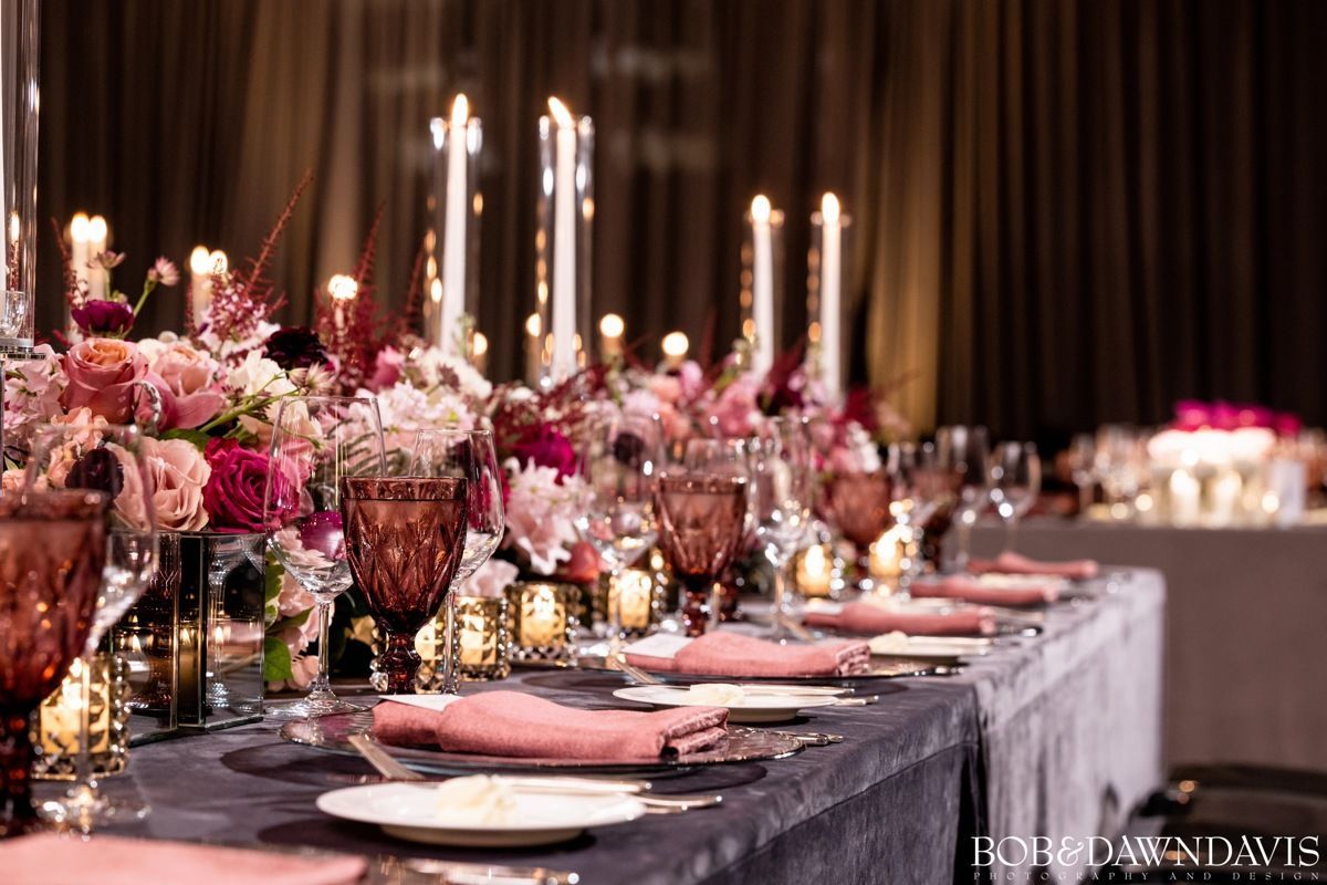 A long table with plates , candles , and flowers on it.