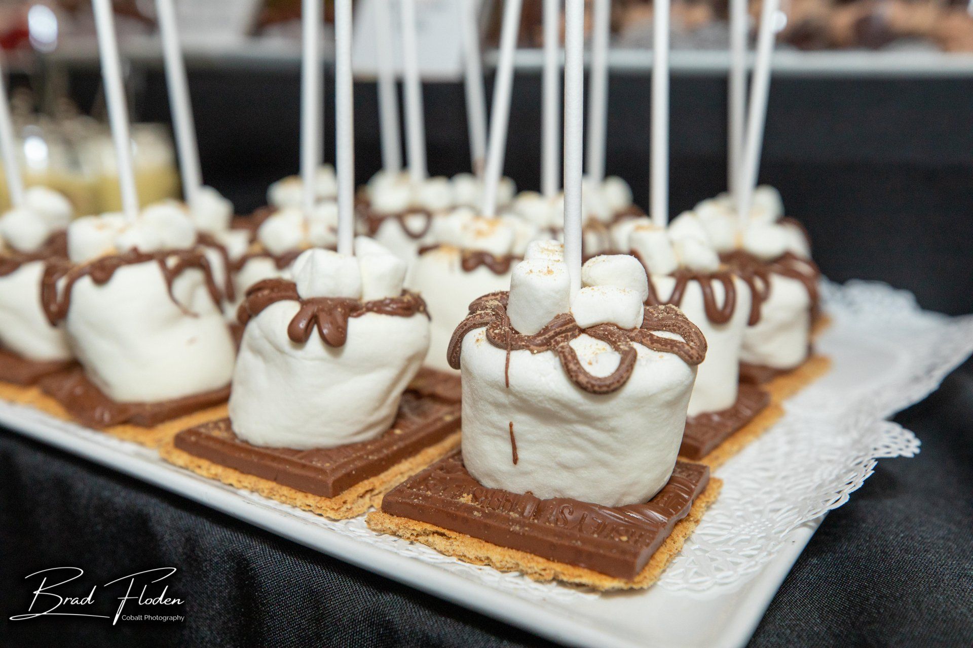 A white plate topped with s'mores and marshmallows on sticks.