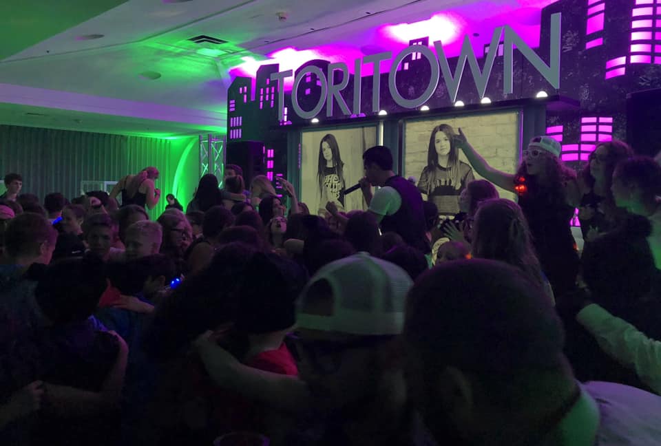 A crowd of people are gathered in a room with a sign that says ' priority ' on it.