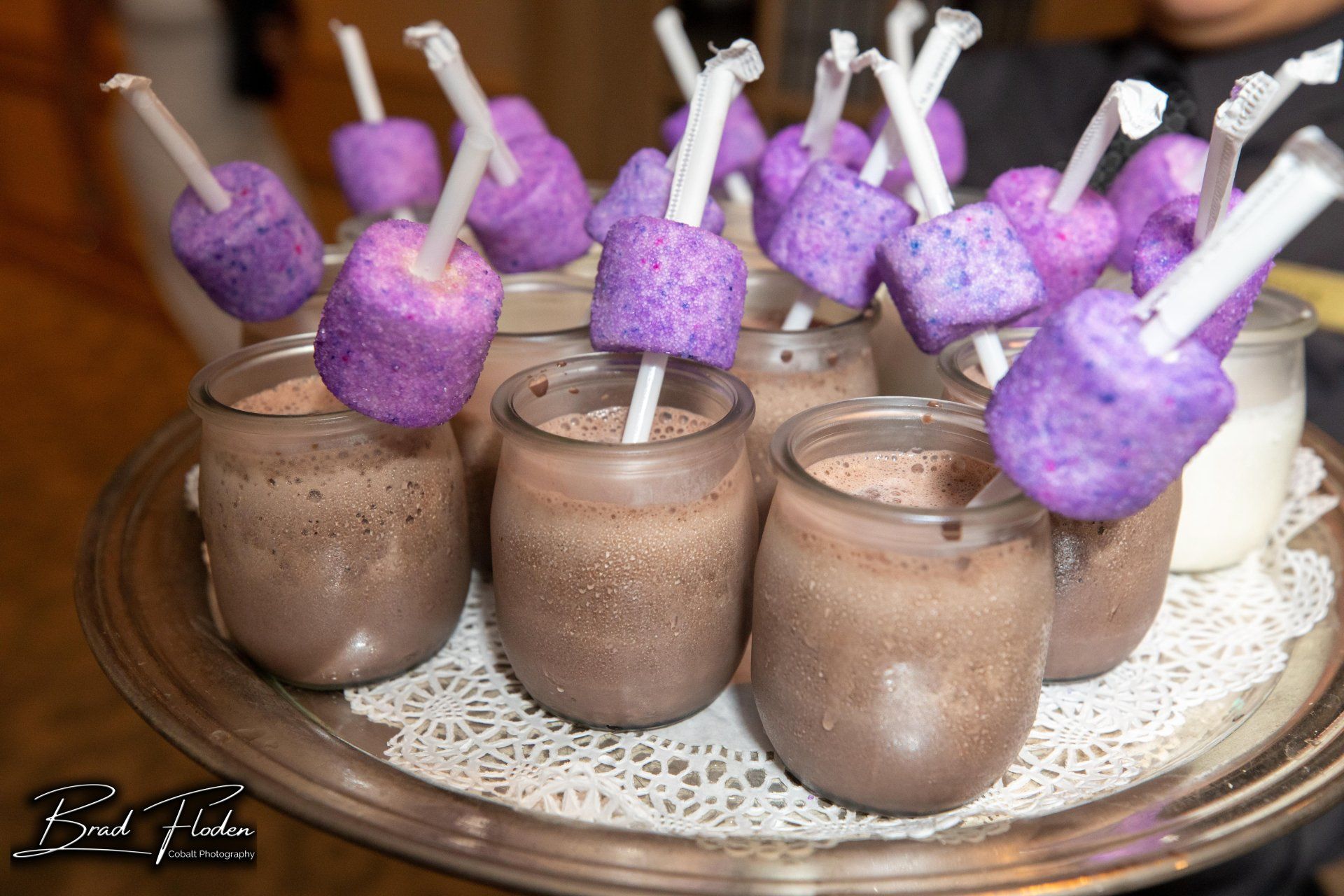 A tray of chocolate pudding with purple marshmallows on sticks.