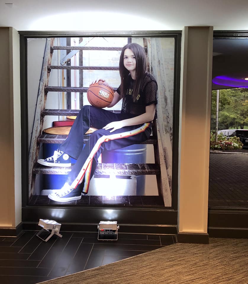A woman is sitting on a set of stairs holding a basketball
