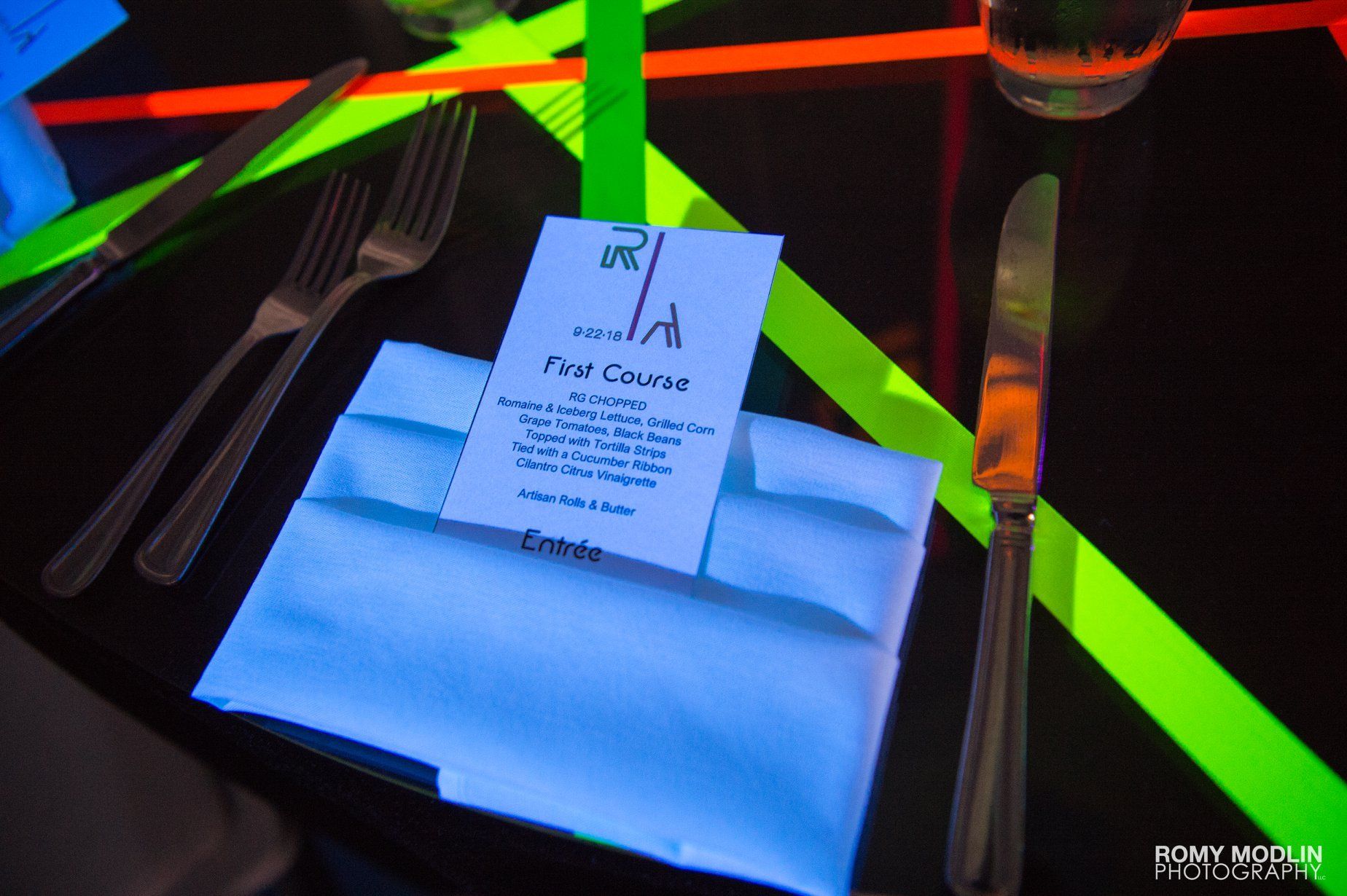 A glow in the dark place setting with a menu on a napkin