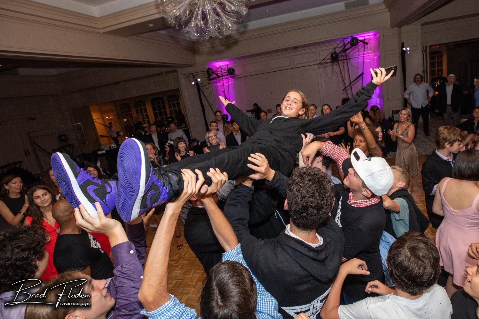 A girl is being lifted in the air by a group of people at a party.