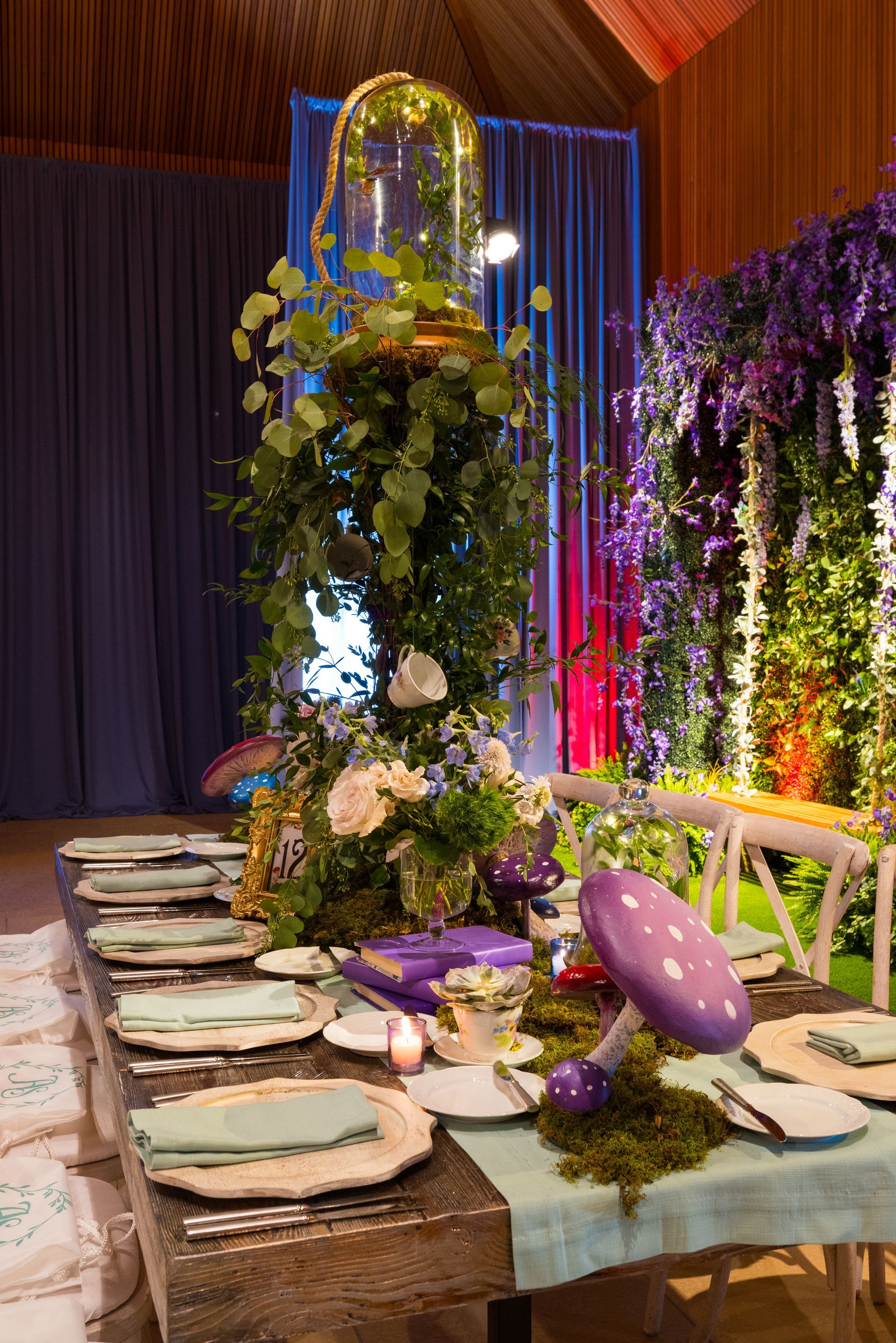 A long table with plates , utensils , and flowers on it.
