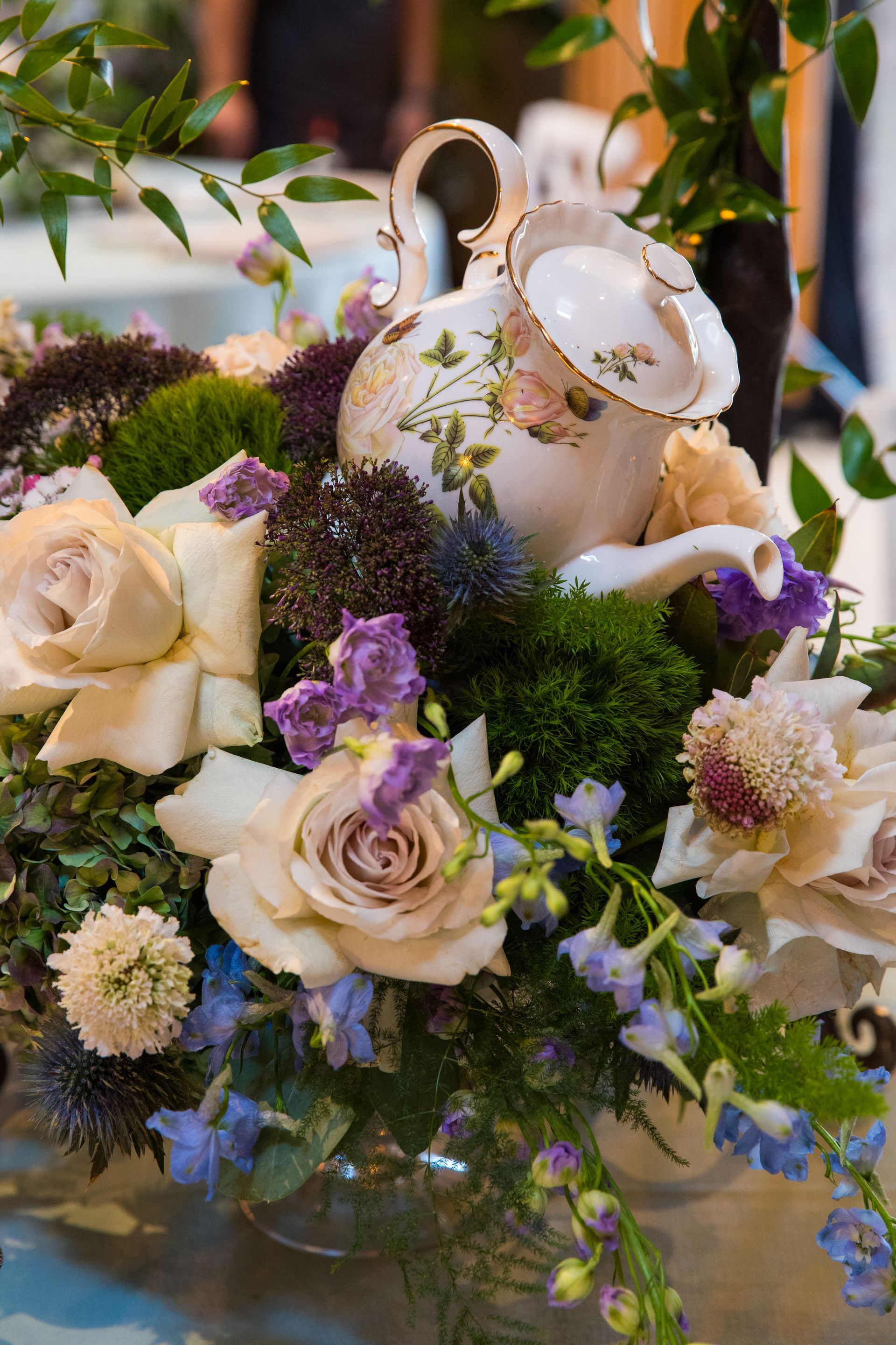A teapot is sitting on top of a table surrounded by flowers.