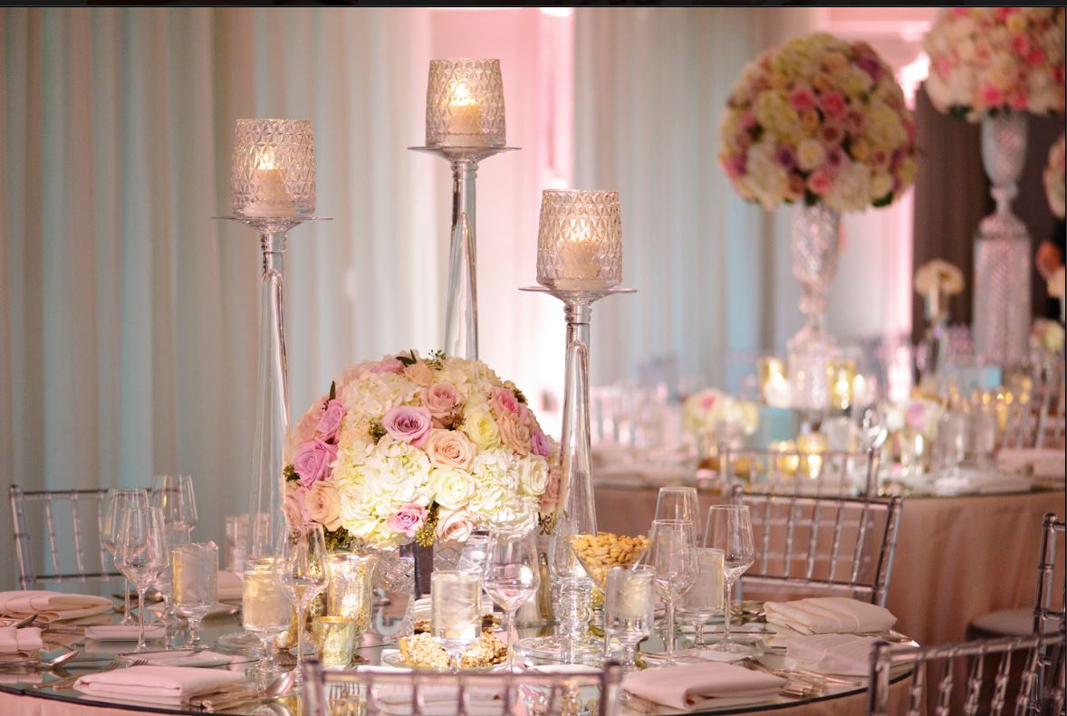 A table set for a wedding reception with candles and flowers on it.